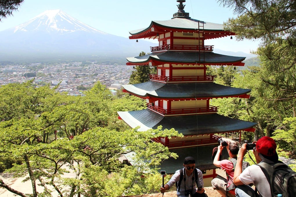 Foreign visitors take a picture of world heritage site Mt. Fuji (back) and a five-story pagoda in Arakurayama Sengen Park in Fujiyoshida. Photo: Kyodo