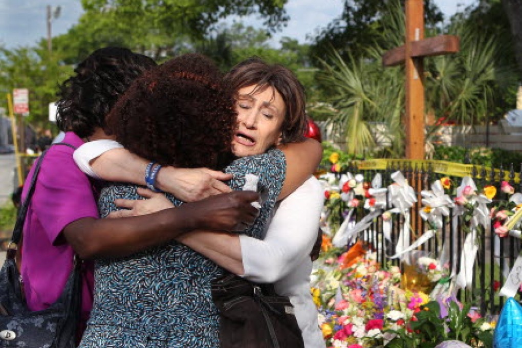 From left, Patricia Bailey, Carol Reid and Maria Bornhorst console each other while visiting the sidewalk memorial in front of the Emanuel AME Church in Charleston. Photo: AP
