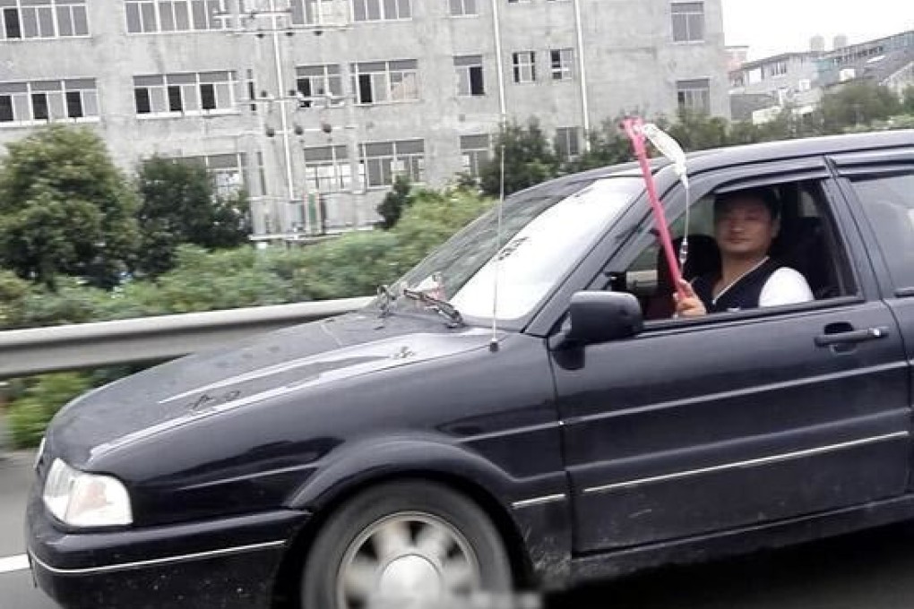 The Chinese motorist is photographed by police driving while holding the pole with the intravenous drip stuck out the side window. Photo: Tencent