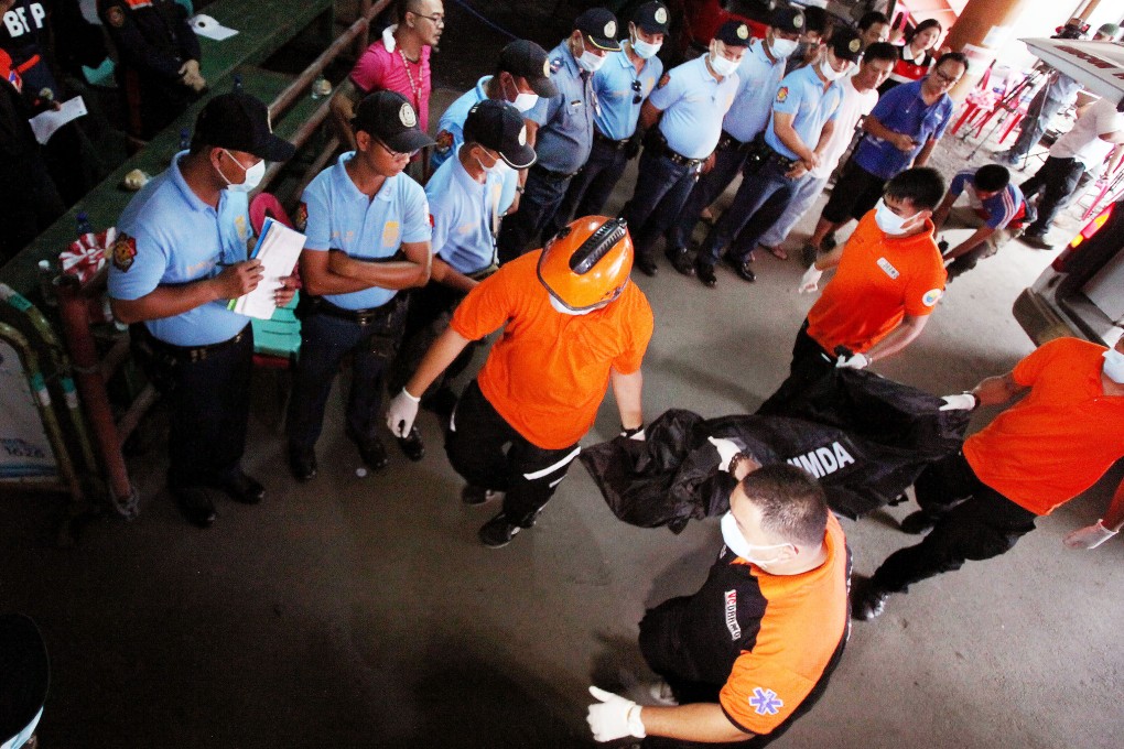 Filipino rescue workers carry a body bag containing one of the bodies of the employees who were killed in the factory fire in Valenzuela City in May. Photo: Xinhua