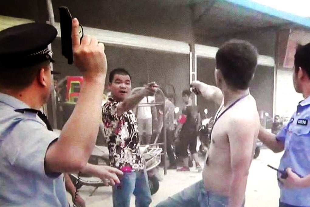 An officer draws his pistol as a fight gets out of hand over stall spaces at a market in Shenzhen on Sunday. Photo: Sina Weibo