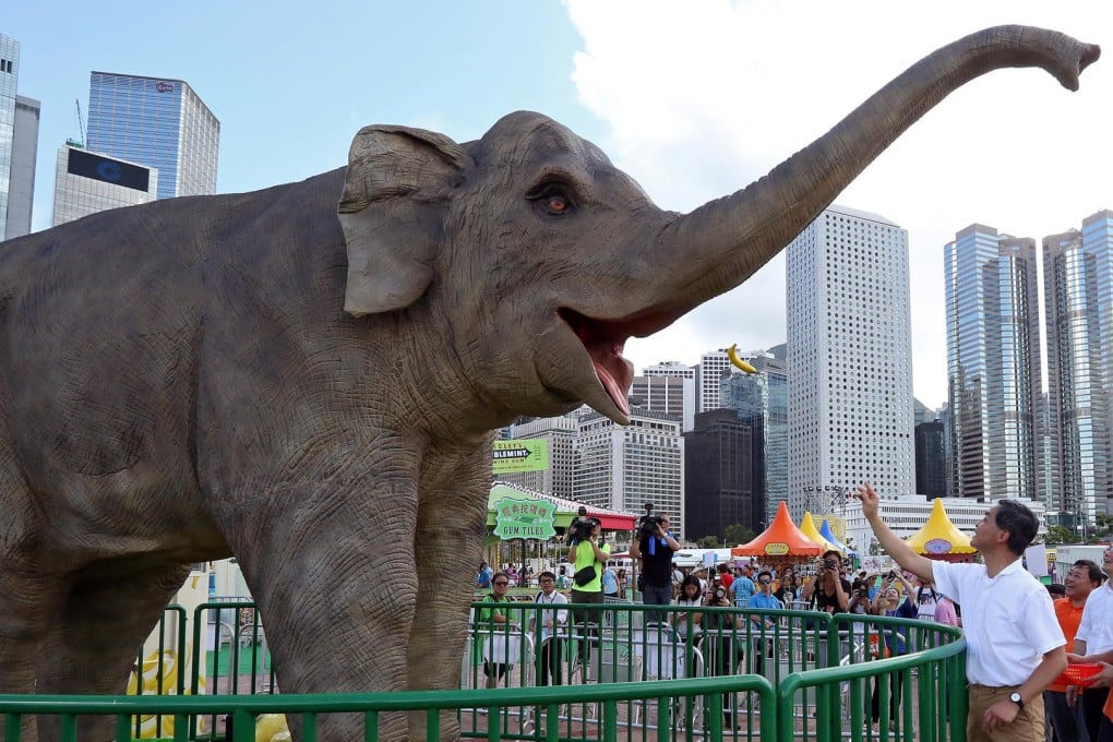 Chief executive Leung Chun-ying feeds bananas to robotic elephant Tino at yesterday's amusement park opening. Photo: Nora Tam