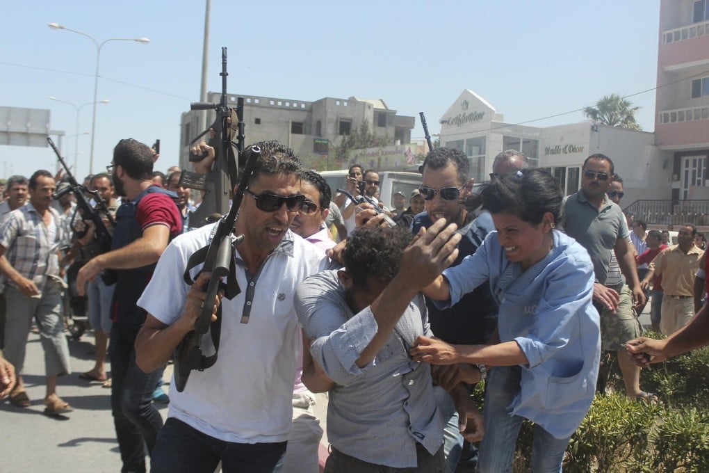 A woman tries to grab one of the suspected gunmen believed to be responsible for opening fire on a beachside hotel in Sousse, Tunisia, as armed police escort him from the scene.Photo: Reuters