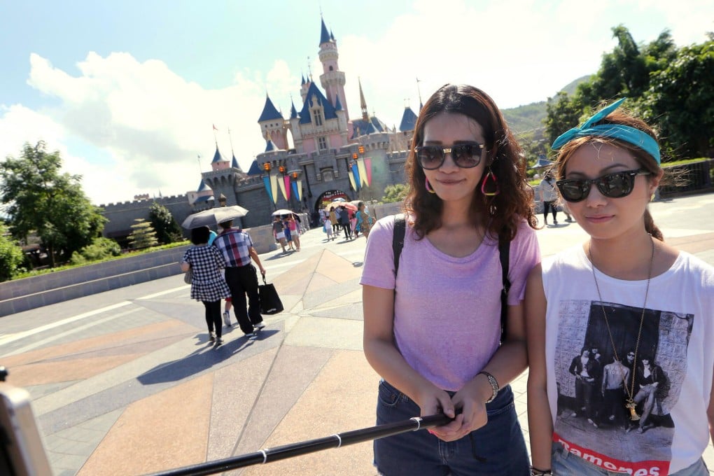 Tourists use a selfie stick at Hong Kong Disneyland