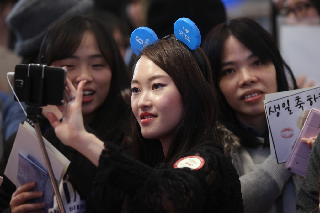A woman uses a selfie stick to take a photo of herself in Hong Kong. Photo: Edward Wong