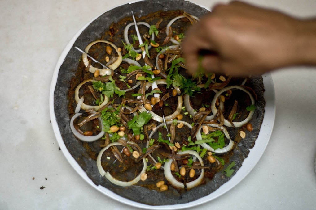 A Malaysian chef puts the final touches on a nasi lemak pizza at the upscale Tujo Bar-serrie and Grill in Kuala Lumpur. Photo: AFP