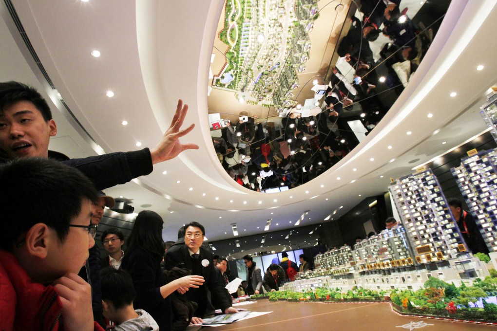 A sales agent speaks to potential buyers in front of a model of Riva, one of the latest developments by Sun Hung Kai Properties, in Hong Kong in 2014. Photo: Reuters