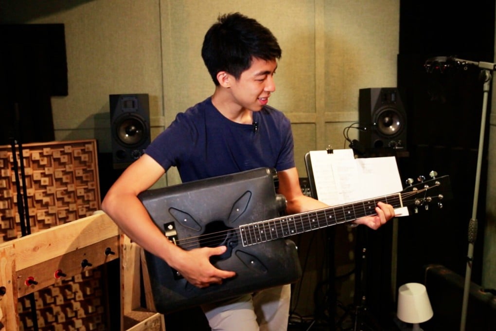 Kevin Cheung holds the guitar he made from a discarded plastic bottle.