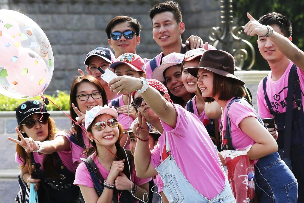 Inside the park, a man composes his photograph at arm's length for a crowded selfie on his phone. Photo: Jonathan Wong