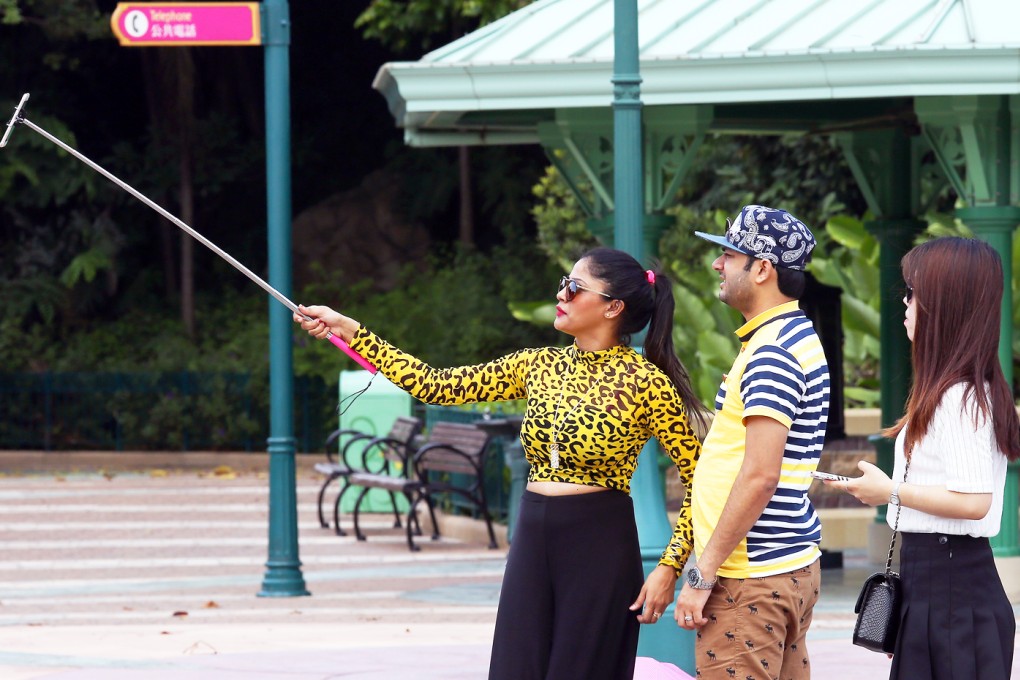 Tourist use selfie stick at the Disneyland in Hong Kong. Hong Kong Disneyland bans use of selfie sticks for safety reasons. Photo: Jonathan Wong