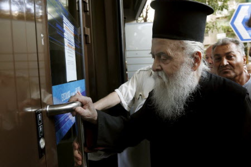 For now, banks in Greece are allowing pensioners, such as Father Theoklitos, 77, a retired Greek Orthodox priest in Athens, to receive a part of their benefits. Photo: Reuters