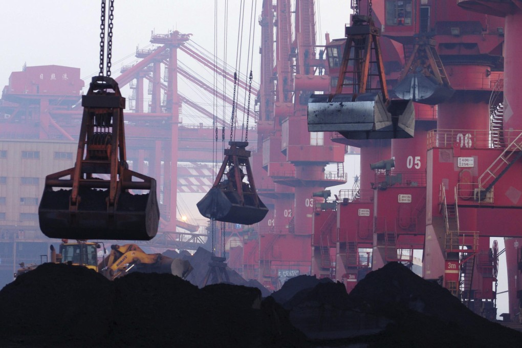 Heavy machines move iron ore at the dock in Rizhao in Shandong province. China's huge demand for commodities is slowing. Photo: AP