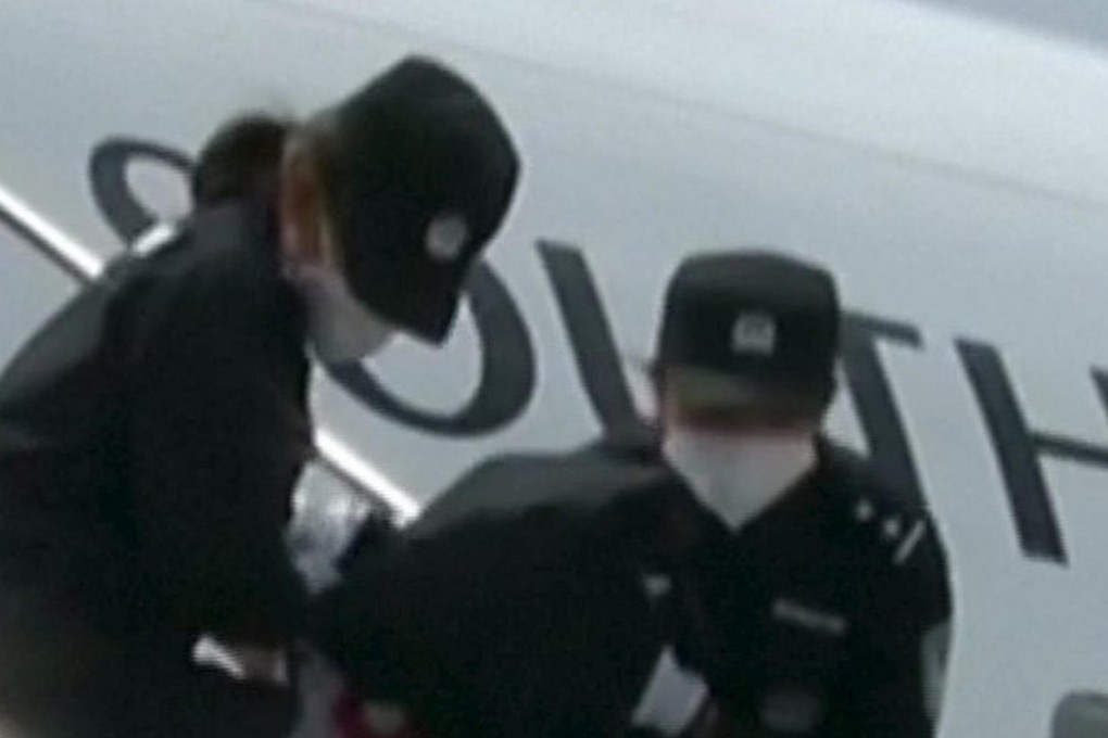People deported from Thailand are brought off an airplane by police at an unidentified location in China on Thursday. Photo: Reuters