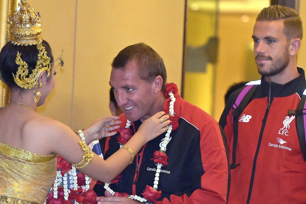 Liverpool manager Brendan Rodgers receives a flower garland, with captain Jordan Henderson looking on, in Bangkok yesterday.Photo: AFP