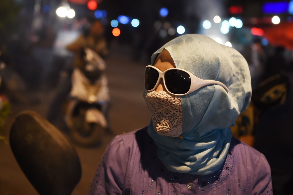 An Uygur woman wears a lace veil at a market in Kashgar. Sales have been hit since China's Xinjiang authorities banned the use of veils and other Islamic coverings. Photo: AFP