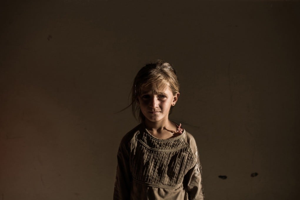 A Syrian refugee girl stands in a building in the Syrian Kurdish city of Amuda, after running away from clashes between regime forces and Islamic State. Photo: AFP