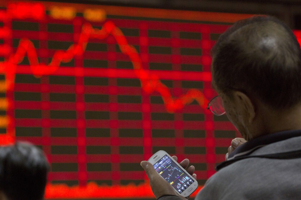 An investor peers at his mobile while keeping an eye on Chinese stock prices as Baring forecasts emerging market stocks will likely deliver 25 per cent less to investors over the coming decade. Photo: AP