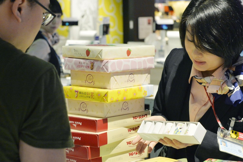 A duty-free store clerk serves customers at Narita airport near Tokyo. Photo: Kyodo