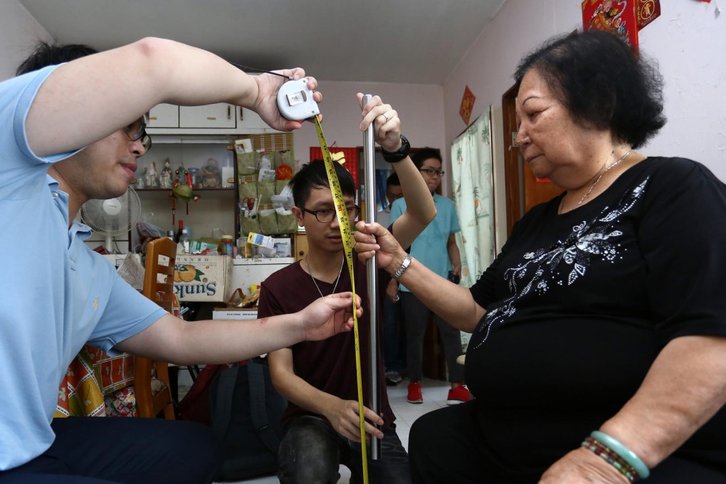 Ray Tang (left) and Vincent Mo from Longevity Design House take measurements for a sofa handle for 74-year-old Chan Cheung-tai in her Tsing Yi home. Photo: Jonathan Wong