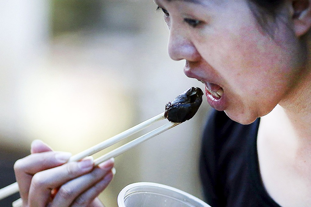 A woman eats dog meat at a festival in Yulin, Guangxi. Photo: Reuters