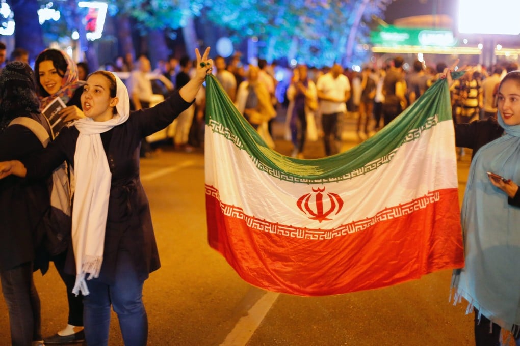 Iranians hold the Iran's national flags as they celebrate in the street of Tehran, after nuclear talks between Iran and world powers ended in Vienna, Austria. Photo: EPA