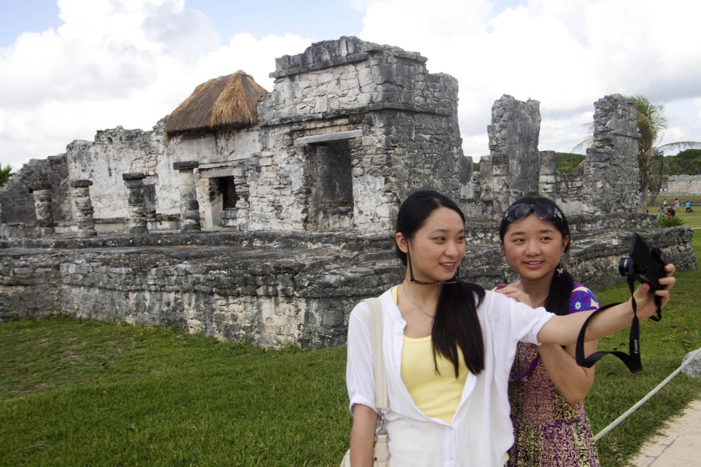 Chinese tourists take selfies of themselves in Cancun, Mexico, as a surge in travel could benefit the shares of online travel agencies like Ctrip and Qunar. Photo: AFP