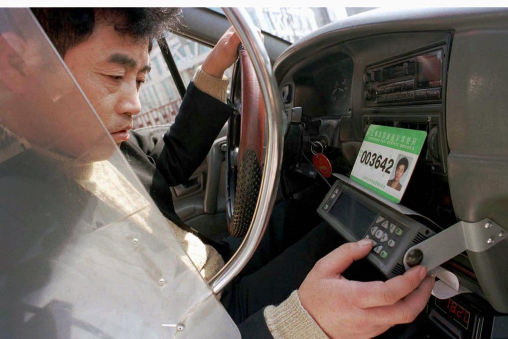 A Shanghai cab driver works on his GPS machine as taxis complain about the competition from outfits like Uber. Photo: Reuters