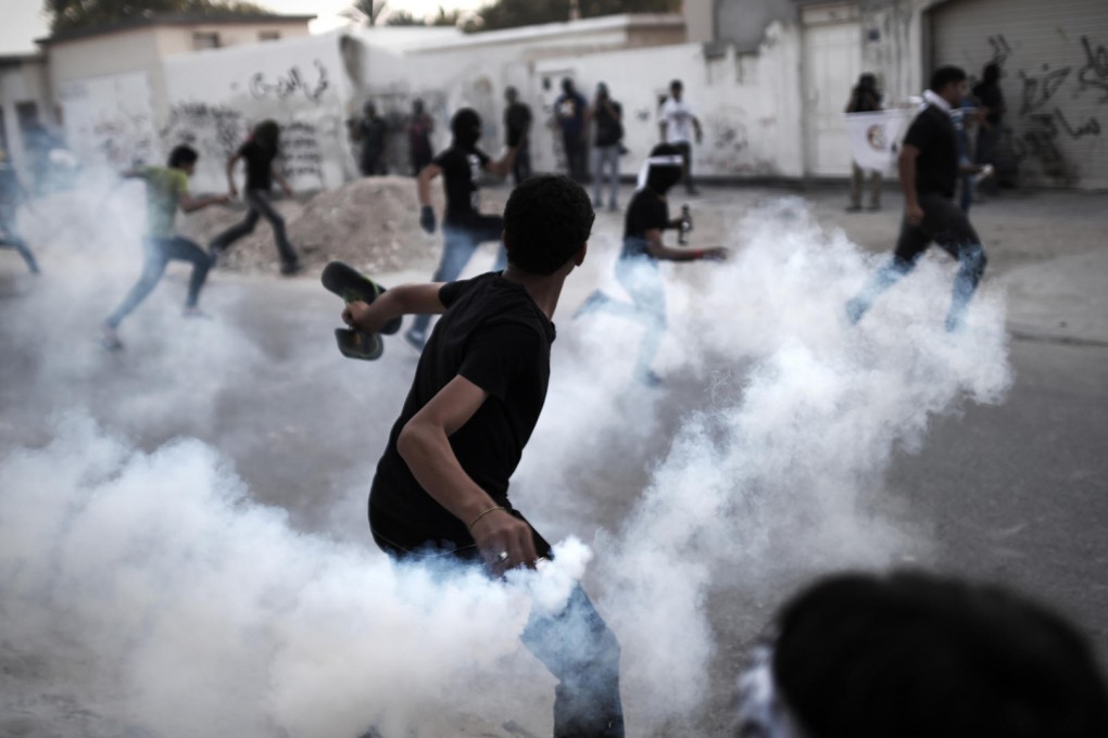 A Bahraini protestor throws a tear gas canister back at riot police during clashes in April last year.
