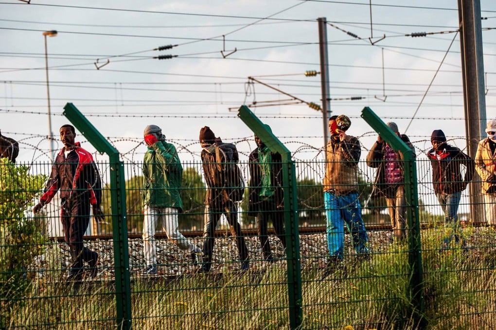 Migrants who successfully crossed the Eurotunnel terminal walk next to the tracks as they try to catch a shuttle to Britain. Photo: AFP