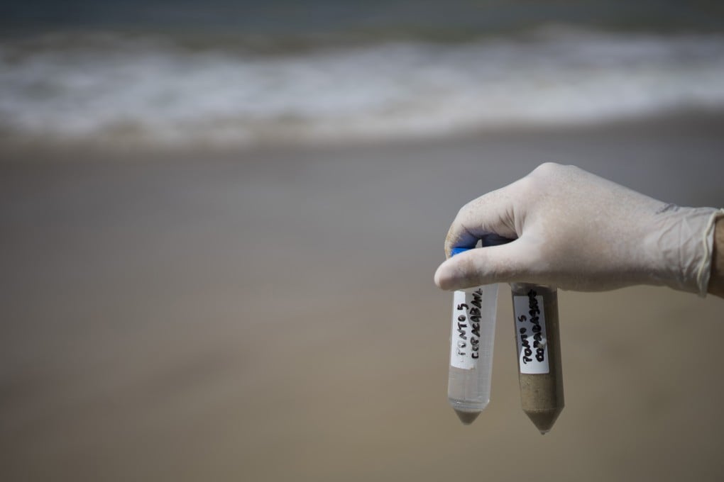 In this April 28, 2015 photo, Fernando Spilki, the head of the environmental studies program at Feevale University, holds up water samples taken from the Copacabana Beach in Rio de Janeiro, Brazil. Spilki's testing looked for three different types of human adenovirus that are typical "markers" of human sewage in Brazil. In addition, he tested for enteroviruses, the most common cause of upper respiratory tract infections in the young. (AP Photo/Felipe Dana)