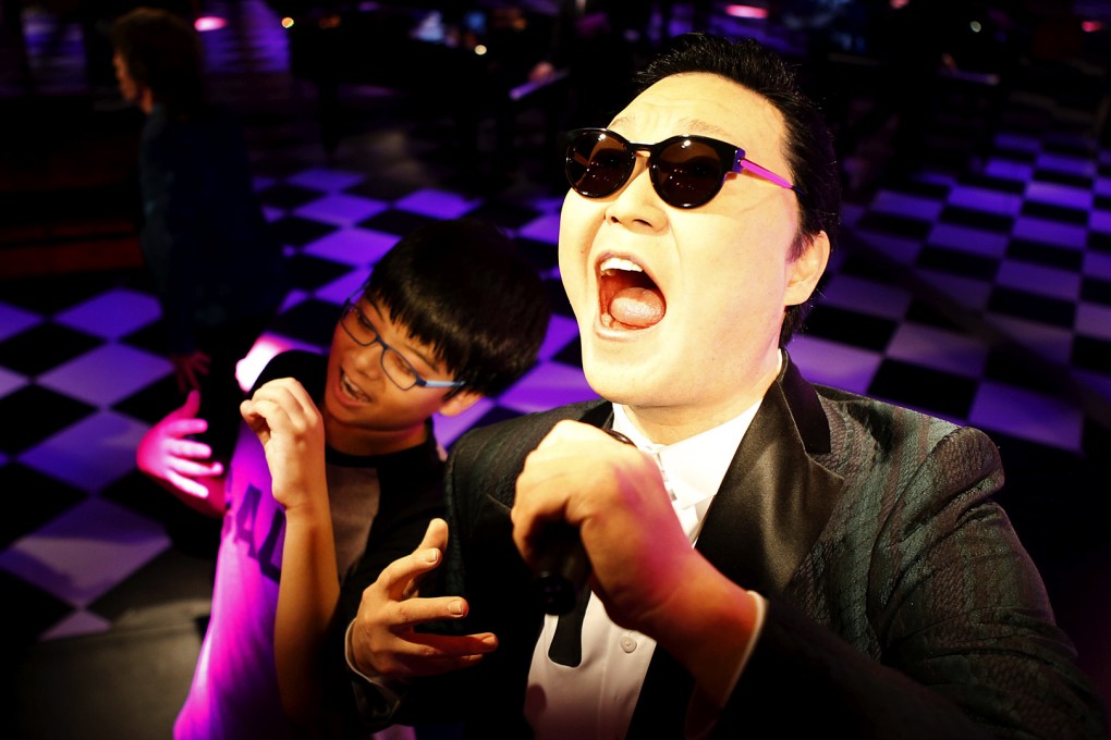 A boy poses for photographs next to the wax figure of South Korean singer Psy at Grevin Wax Museum in central Seoul, South Korea. Photo: Reuters