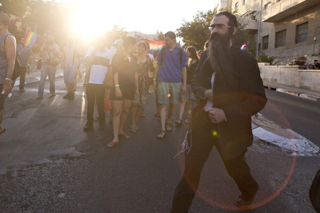 Yishai Schlissel reaches into his jacket before pulling out a knife and going on a rampage at a Jerusalem gay pride march on Thursday. Photo: AP