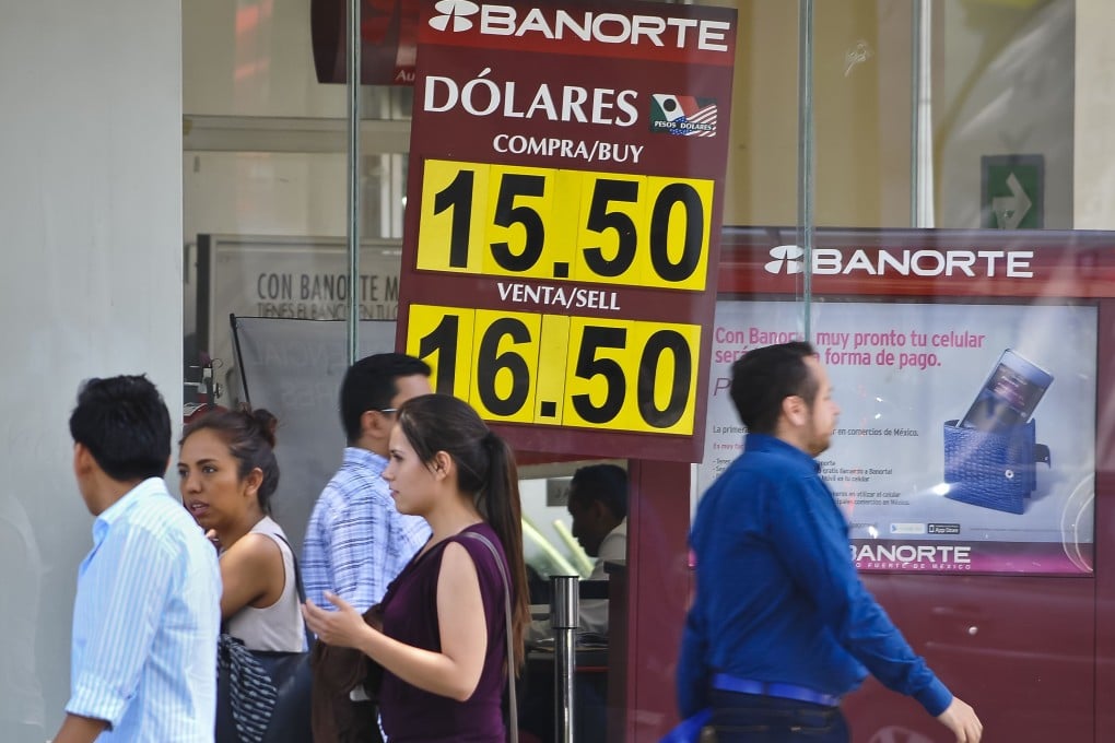People walk by a sign showing the exchange rate between the Mexican peso and US dollar as Mexico's central bank vowed to  defend the local currency. Photo: AFP