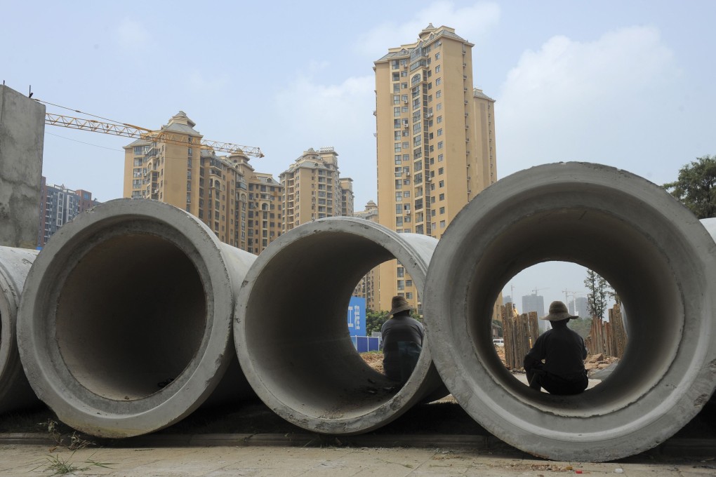 Labourers sit in cement pipes near residential buildings at a construction site in Wuhan, Hubei province. Mainland media have estimated the entire pipeline project across the nation could cost 1 trillion yuan a year. Photo: Reuters