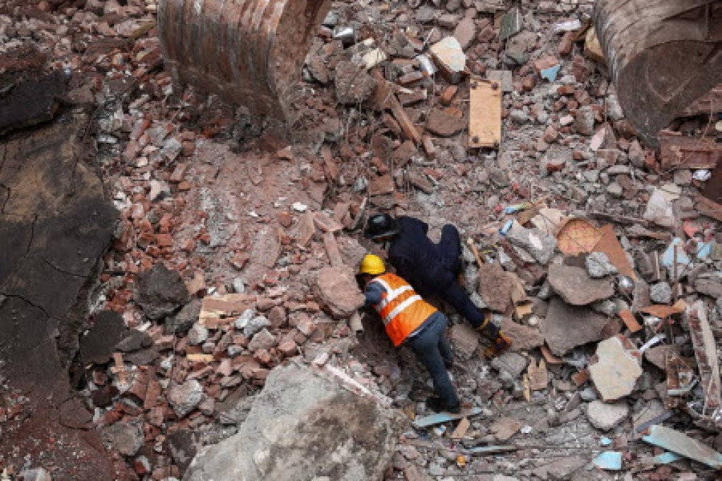 A member of the National Disaster Response Force and an Indian fire brigade worker search for trapped victims. Photo: EPA