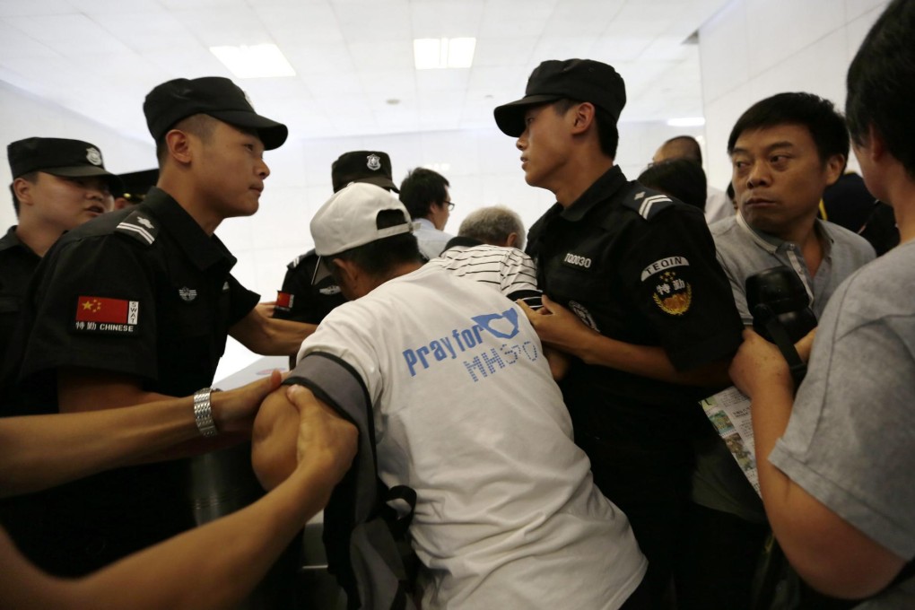 Anxious relatives of Chinese passengers on missing flight MH370 are stopped by police as they approach a Malaysia Airlines office in Beijing yesterday to seek answers. Photo: EPA