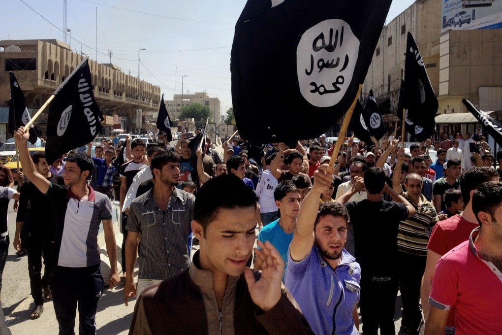 Demonstrators chant pro-Islamic State slogans as they carry the group's flag in front of the provincial government headquarters in Mosul. Photo: AP