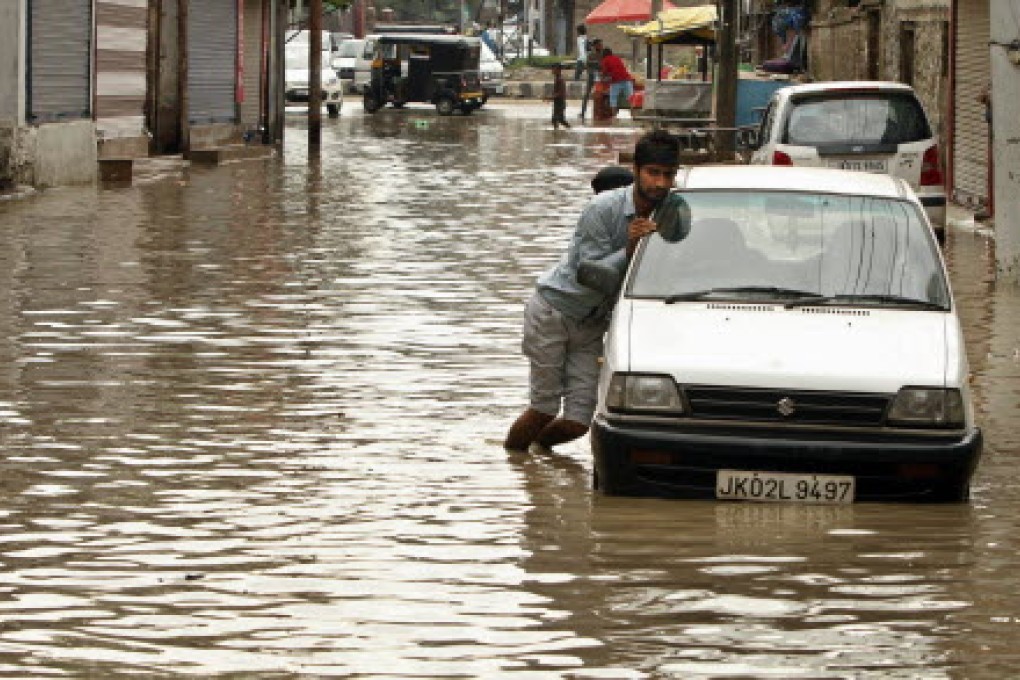 A Kashmiri man pushes his car stuck in a flooded street after heavy rains in Srinagar, India, earlier this month. Photo: AP