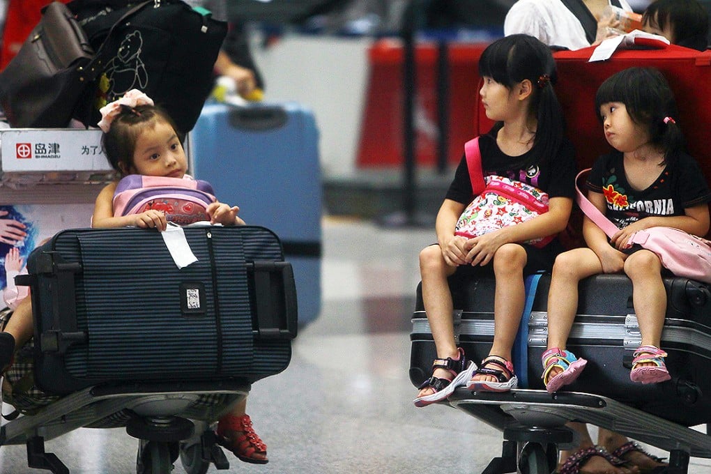 Children sit on luggage carts at Beijing Capital International Airport after flights were cancelled due to bad weather. Photo: AP