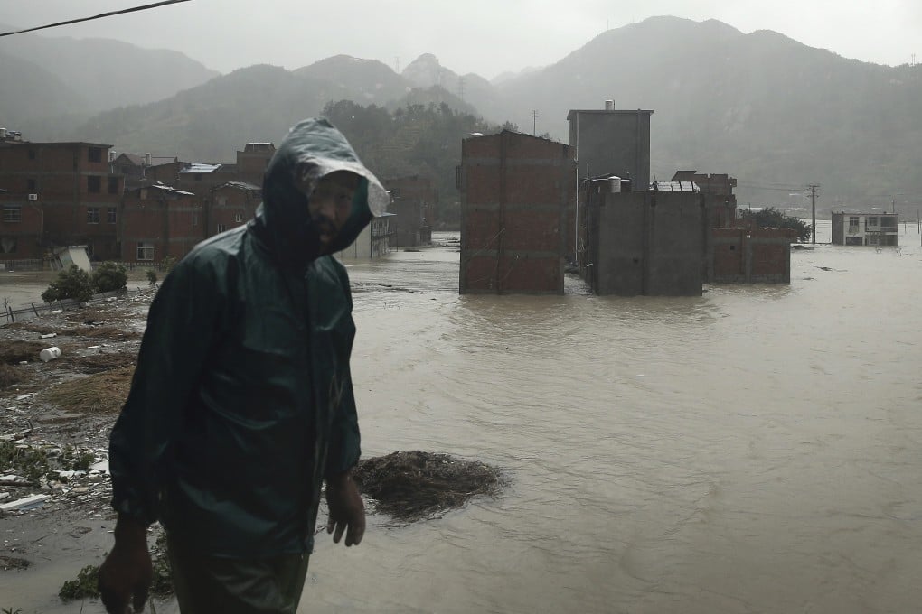 A man walks past a village in Ningde in Fujian province submerged in water after it was hit by Tyhpoon Soudelor. Photo: AP