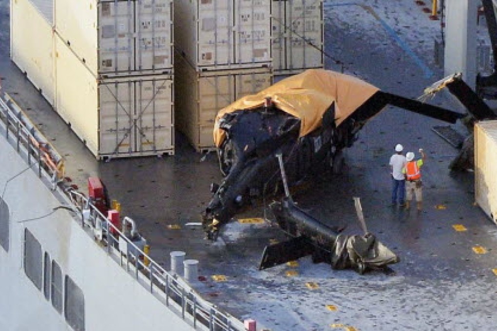 US military helicopter is pictured on the cargo ship, with its tail broken off and its body partly covered with an orange tarp. Photo: Kyodo