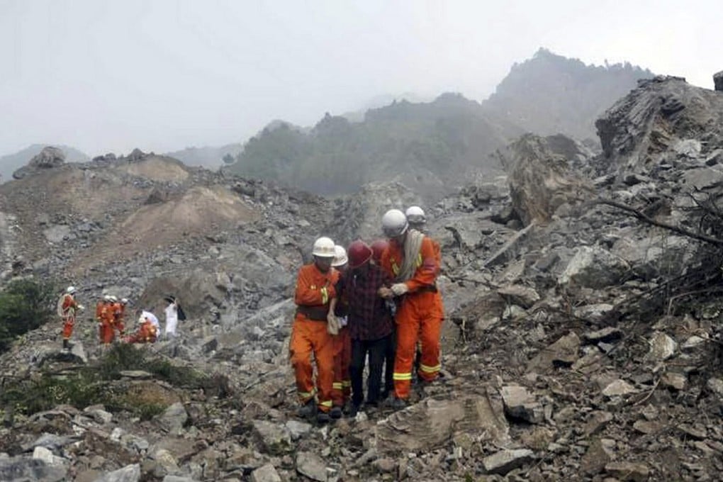 Rescue workers lead a survivor to safety. Many people were reportedly trapped under the rock and soil in the disaster and more than 700 rescuers have been deployed to search for them. Photo: Imaginechina