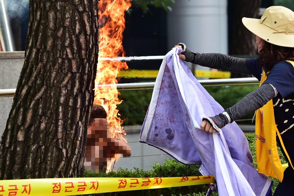 A man sets himself on fire as a South Korean woman tries to extinguish the flames outside the Japanese embassy in Seoul. Photo: AFP