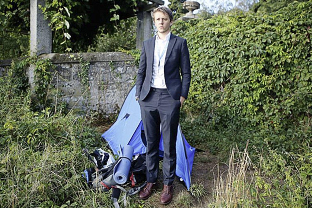 The unpaid UN intern stands next to his tent and mattress.