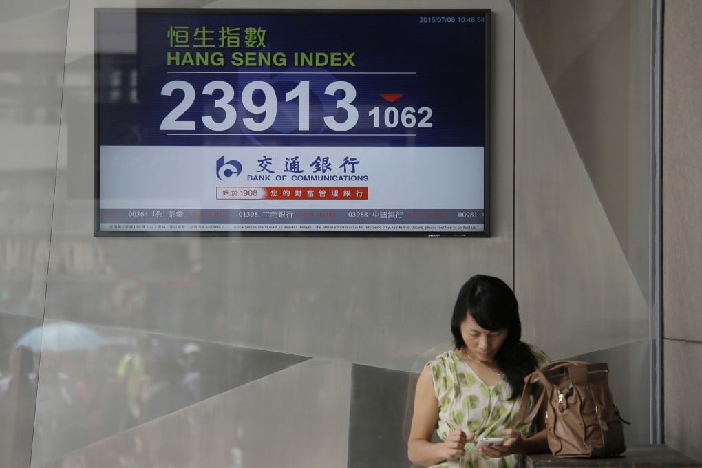 A woman stands in front of a screen showing the Hong Kong Hang Seng index near a local bank. Photo: AP