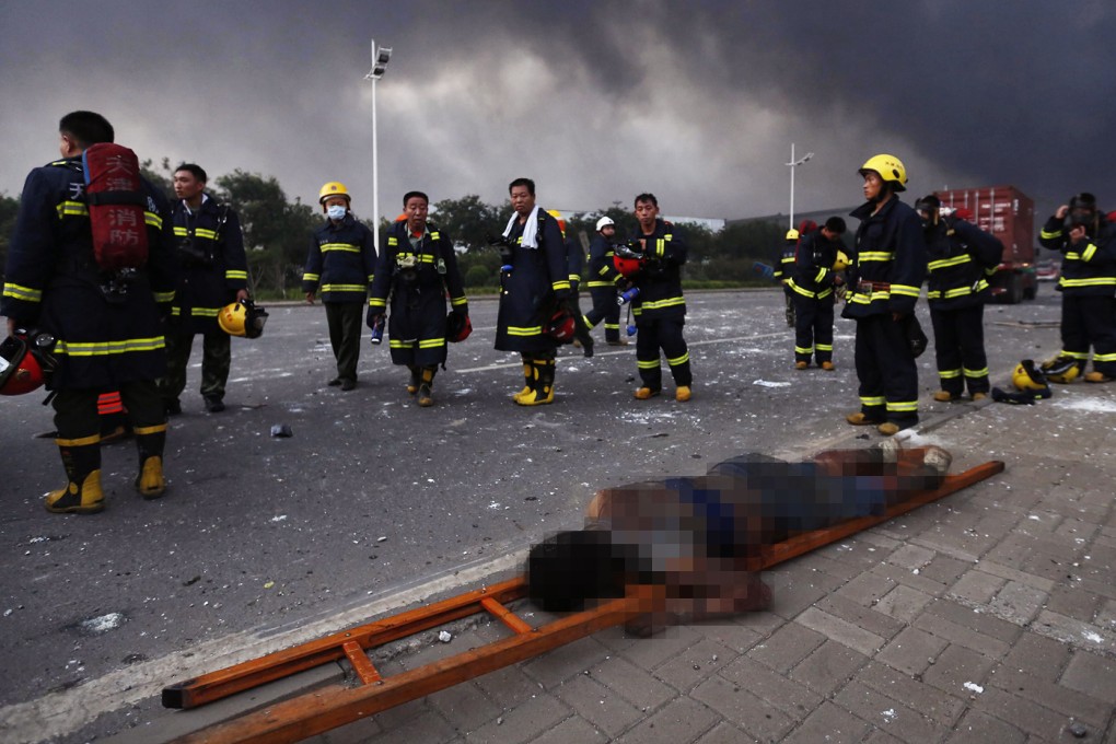 Firefighters in Tianjin walk past a victim of last night's explosions. Photo: EPA