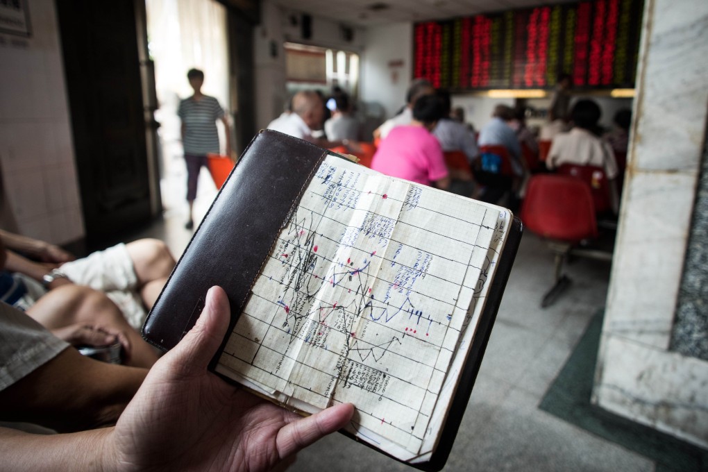 An investor holds a notebook showing stock market movements, as he sits at a brokerage house in Shanghai. Photo: AFP