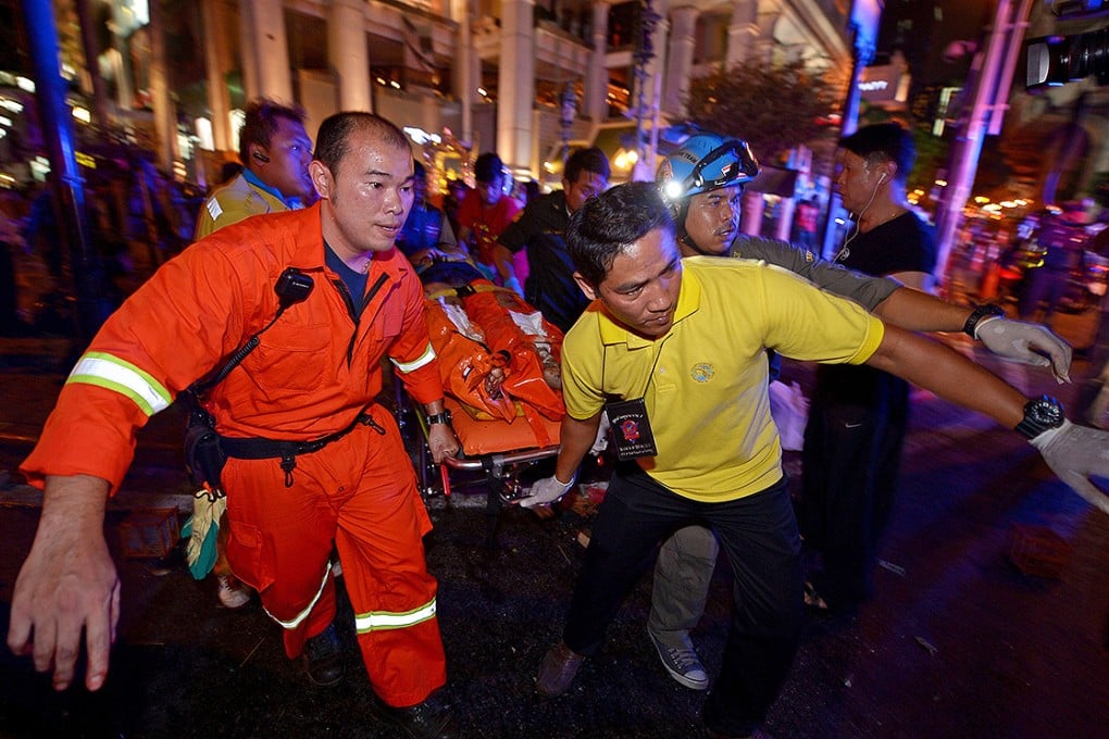 Thai rescue workers carry an injured person after a bomb exploded outside a religious shrine in central Bangkok. Photo: AFP