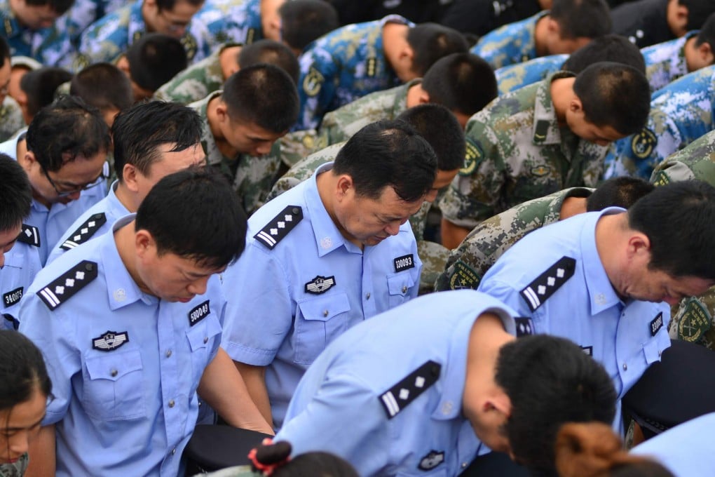 Soldiers, police officers and paramilitary policy bow their heads at a ceremony on Tuesday to mourn the victims of Tianjin's explosions. Photo: Xinhua