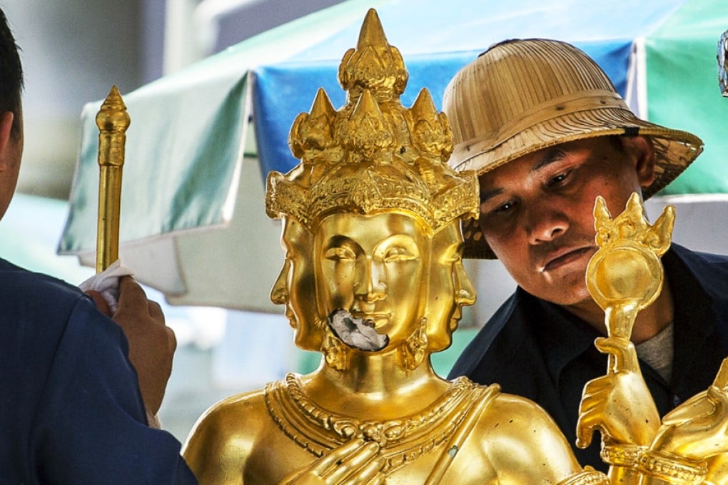 Workers clean a statue of Hindu god Brahma at the Erawan shrine. Photo: Reuters